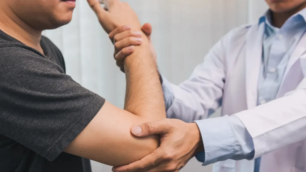 Photo of a physiotherapist treating a patient’s wrist or elbow, in a bright clinic setting.